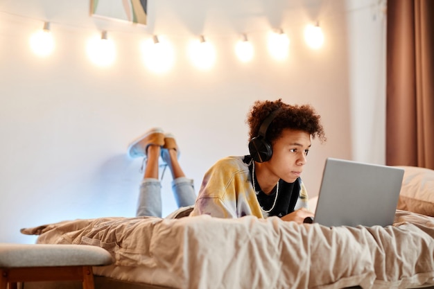 Jugendlich Junge, der Laptop auf Bett verwendet