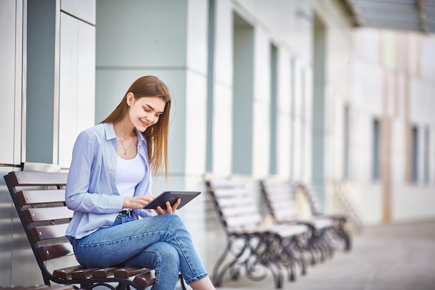 Jugendlich Mädchen, das auf einer Bank mit einem Tablet in ihrer Hand sitzt Kopieren Sie Platz