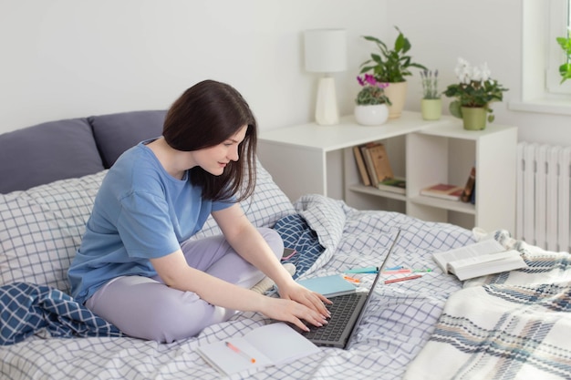 Jugendlich Mädchen, das zu Hause auf Bett mit Laptop studiert