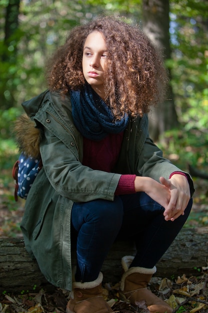 Jugendlich Mädchen des gelockten Haares im Herbstwald