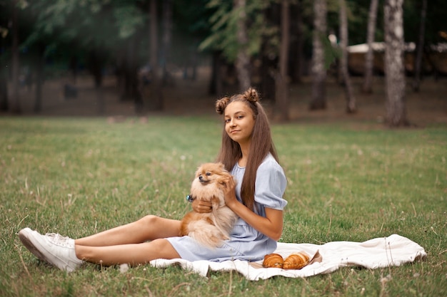 Jugendlich Mädchen mit kleinem Hund des Haustiertiers auf einem Picknick im Freien.