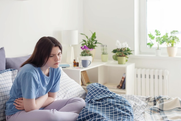 Jugendlich Mädchen mit Magenschmerzen auf Bett