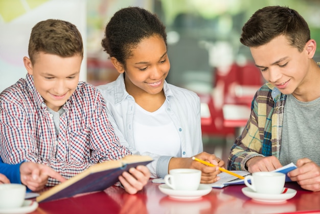 Jugendliche, die bei Tisch im Café Tee studierend und trinkend sitzen