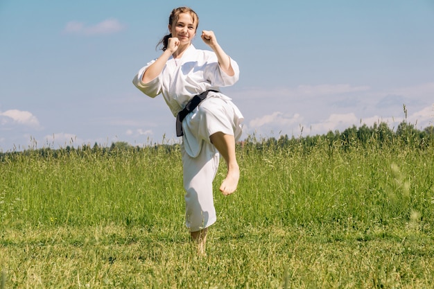 Jugendliche, die draußen Karate-Kata praktiziert, bereitet sich auf Yoko Geri Kick vor