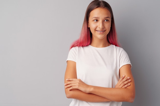 Jugendlicher des jungen Mädchens mit dem rosa Haar glücklich und über grauem Hintergrund lächelnd