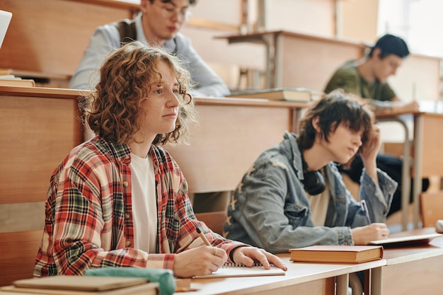 Foto jugendlicher ernsthafter student, der auf die tafel schaut und dem lehrer zuhört