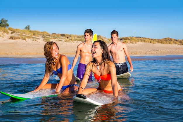 Jugendlichersurfjungen und -mädchen, die ove Surfbrett schwimmen