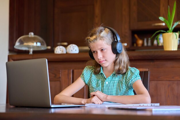 Jugendliches Mädchen mit Laptop- und Kopfhörerstudien zu Hause