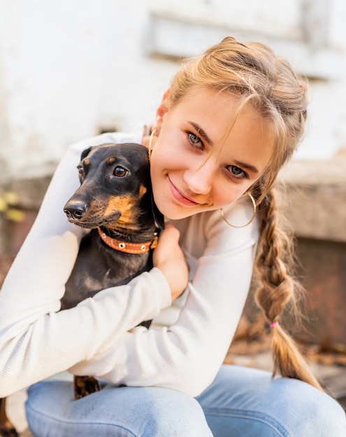 Jugendlichmädchen, das draußen ihren Dachshundhund umarmt