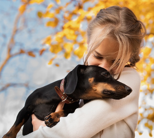 Jugendlichmädchen, das draußen ihren dachshundhund umarmt