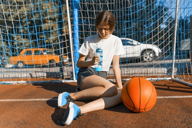 Jugendlichmädchen, das Straßenbasketball mit Ball spielt