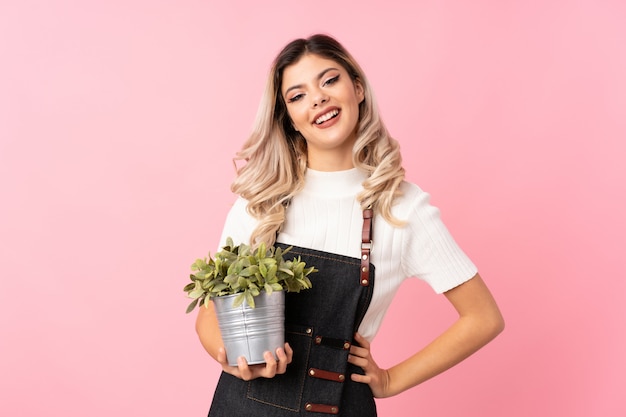 Jugendlichmädchen über dem lokalisierten Rosa, das einen Blumentopf nimmt