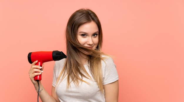 Jugendlichmädchen über Rosa mit Haartrockner