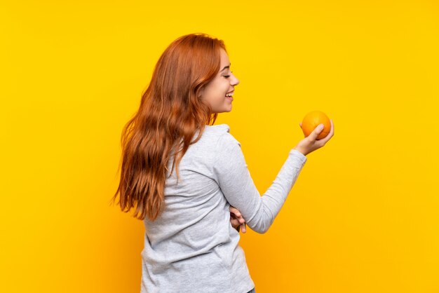 Jugendlichrothaarigemädchen, das eine Orange über lokalisiert hält