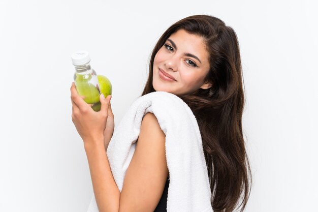 Jugendlichsportmädchen über lokalisierter weißer Wand mit einem Apfel und einer Flasche Wasser