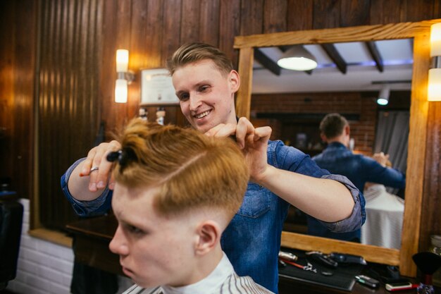 Jugendrothaarigejungen-Haarschnittfriseur im Friseursalon