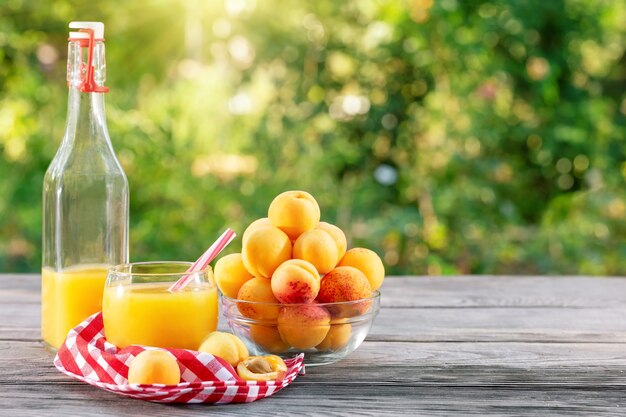 Jugo de albaricoque en botella y vaso y albaricoques en mesa de madera