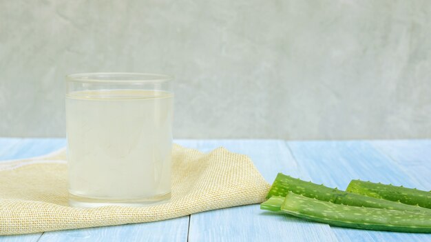 Jugo de aloe vera en una mesa de madera azul.