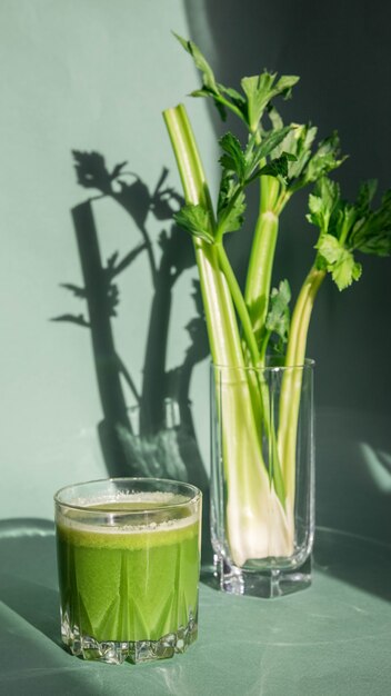 Jugo de apio en un vaso y apio sobre un fondo claro