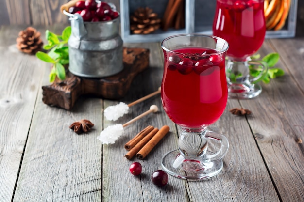 Jugo de arándano fresco con canela y anís en frascos de vidrio sobre la superficie de madera vieja. Enfoque selectivo.