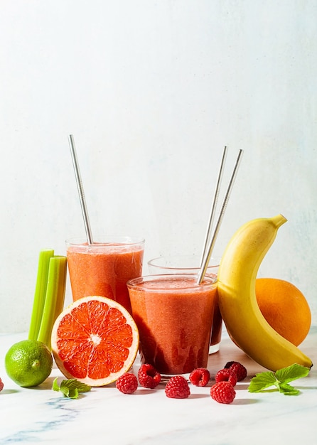 Foto jugo de batido fresco en vasos con tubos de metal sobre la mesa y los ingredientes.