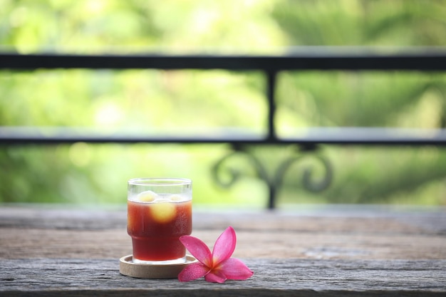 Jugo de bayas y flor de frangipani rosa sobre mesa de madera