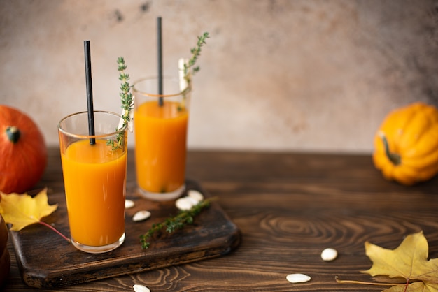 Jugo de calabaza en una botella y vaso sobre una mesa de madera