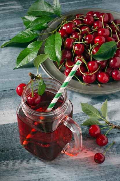 Jugo de cereza en tarro de cristal y cerezas maduras en placa de metal sobre fondo de madera. Ã Â¡lose-up.