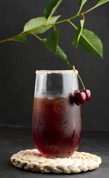 Jugo de cereza en un vaso sobre un fondo negro