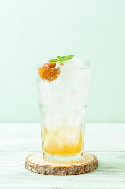 Jugo de ciruela helado con soda y menta en la mesa de madera - bebida refrescante