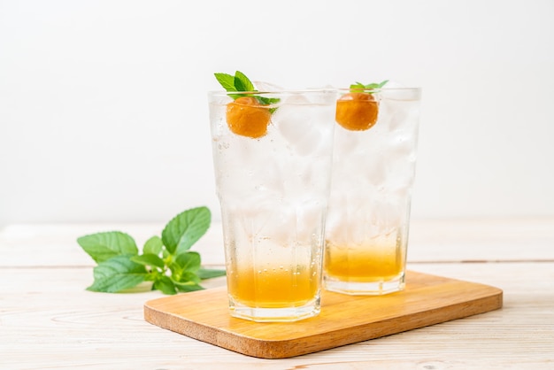 Jugo de ciruela helado con soda y menta en mesa de madera