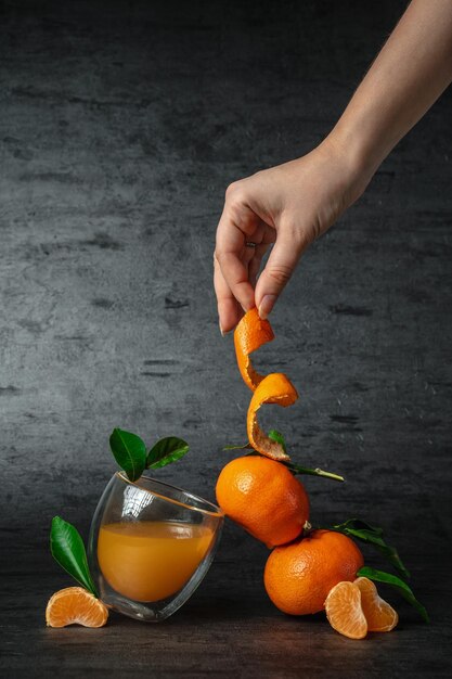 Foto jugo de cítricos recién exprimido jugo de mandarina equilibrio joven sosteniendo mandarina