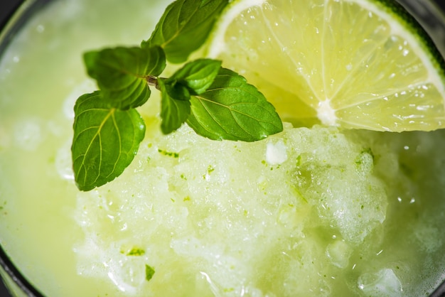 Jugo de cóctel con lima, menta y hielo. Accesorios para bebidas de bar en el fondo de la tabla negra.