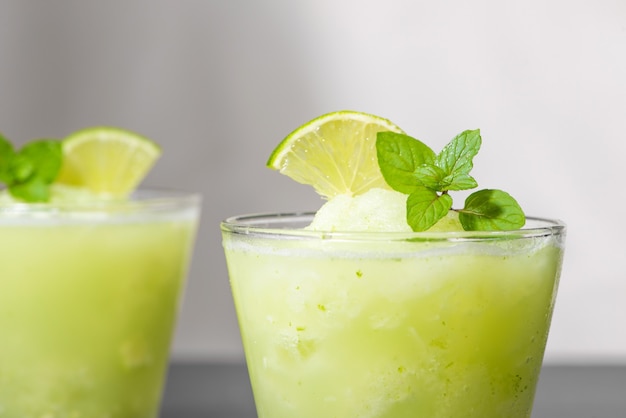 Jugo de cóctel con lima, menta y hielo. Accesorios para bebidas de bar en el fondo de la tabla negra.