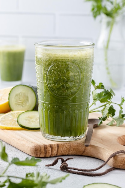 Jugo de desintoxicación verde vibrante refrescante ingredientes nutritivos y de limpieza en la mesa de madera