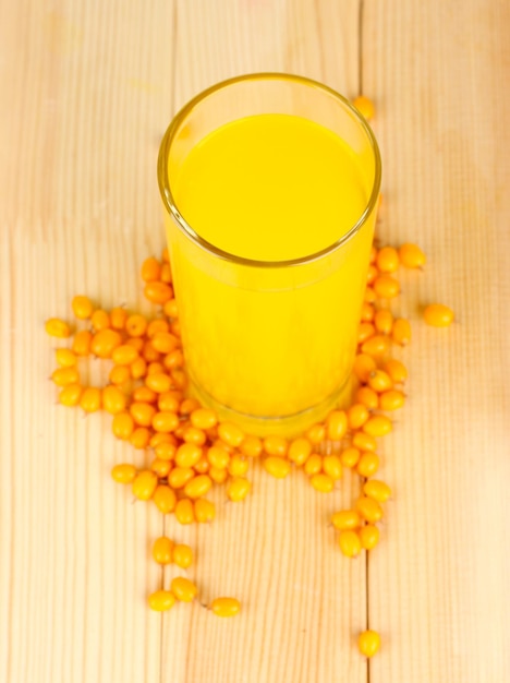 Jugo de espino cerval de mar en un vaso de precipitados sobre fondo de madera closeup