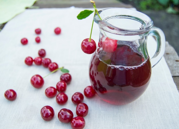 Jugo frío de cereza en tarro y frutos maduros.