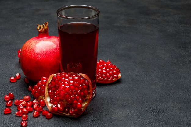 Jugo de granada y semillas en la mesa de hormigón oscuro