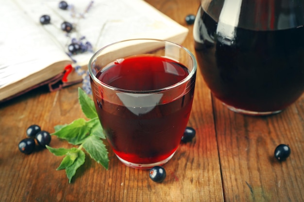 Jugo de grosella fresca con bayas y libro en la mesa de cerca