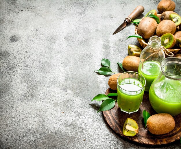 El jugo de kiwi con rodaja de fruta. Sobre mesa rústica.