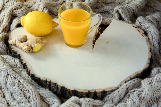 Jugo de limón en un vaso, limón y jengibre en una madera