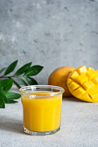 Jugo de mango fresco en un vaso sobre una superficie gris