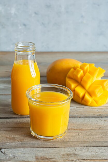 Foto jugo de mango fresco en un vaso de vidrio con rebanada de mango sobre fondo de madera bebida exótica