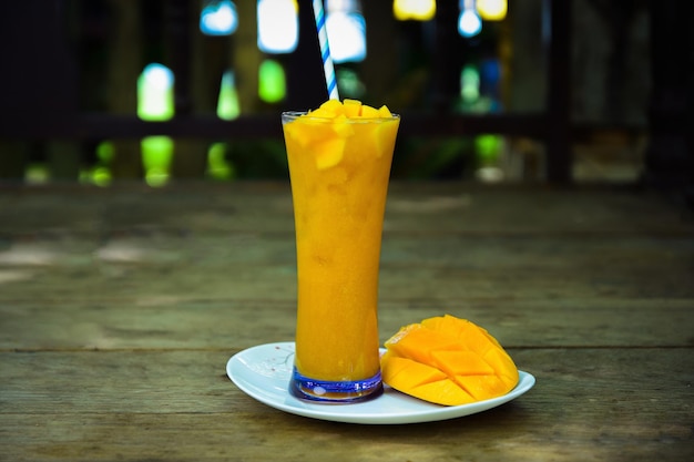 Jugo de mango con rodaja de mango aislado sobre fondo de madera.