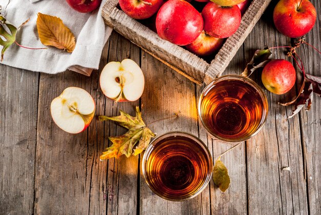 Jugo de manzana de granja orgánica fresca en vasos con manzanas rojas crudas enteras y en rodajas, en la vieja mesa de madera rústica, vista superior de copyspace