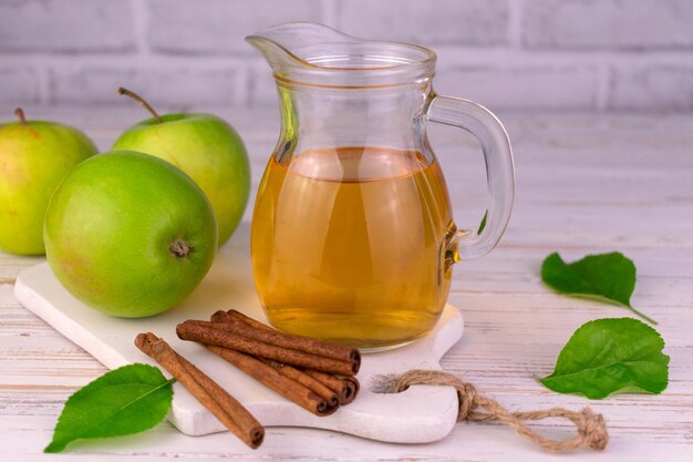 Jugo de manzana en una jarra de vidrio sobre un fondo blanco.