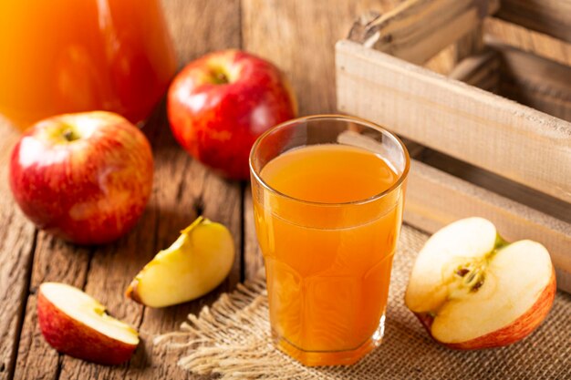 Jugo de manzana y manzanas rojas sobre la mesa.