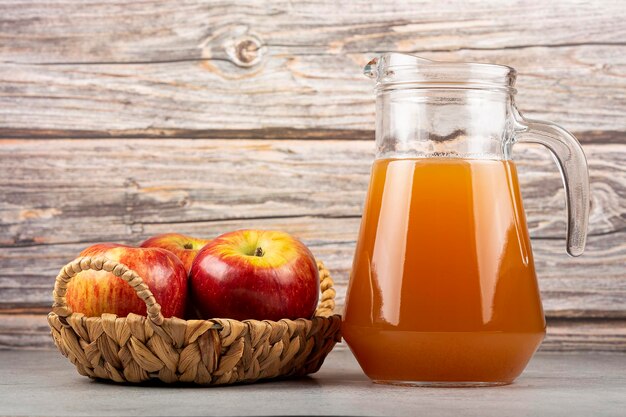 Jugo de manzana y manzanas rojas sobre la mesa.