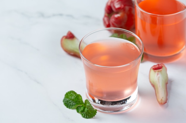 Jugo de manzana rosa sobre superficie blanca