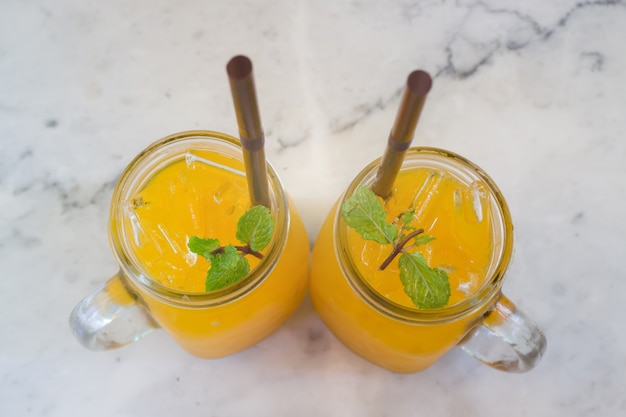 Jugo de naranja con cubito de hielo en la mesa de mármol